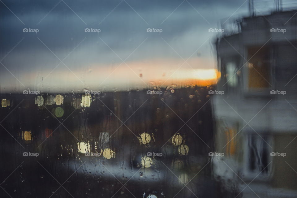 Rainy evening. Water drops on window on sunset background 