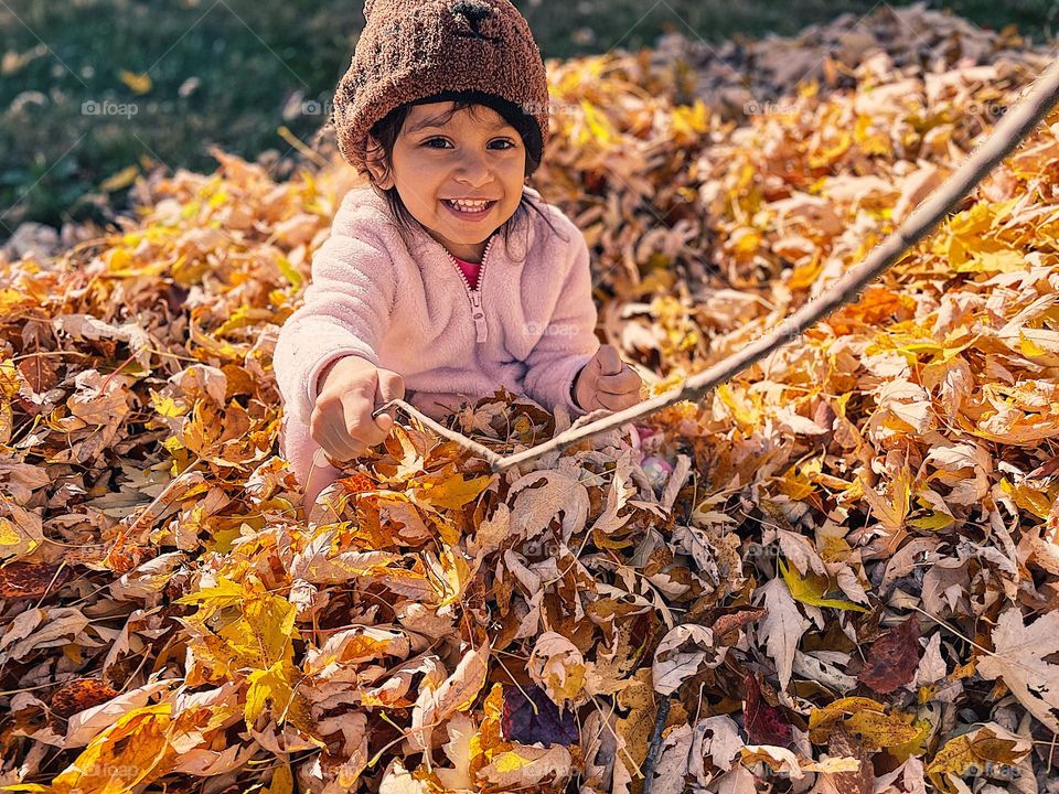 Little girl wears Bear hat in a pile of leaves, fall leaves in a pile, Halloween fun, jumping in piles of leaves, kids having fall time fun
