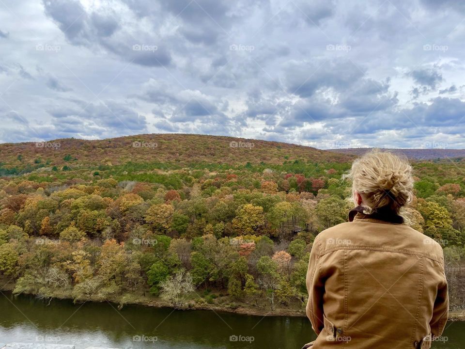 Fluffy clouds, overcast gray blue sky. Women from behind admiring Catskill mountains in autumn