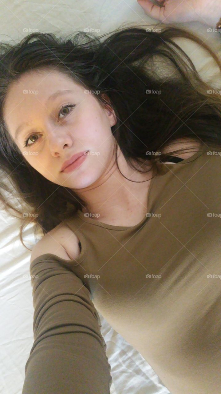 Beautiful teenager girl lying on bed taking selfie