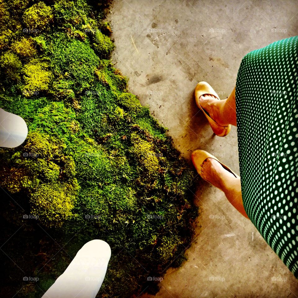 Businesswoman in green polka-dot dress admires the green moss.  Pasadena CA, March 2013