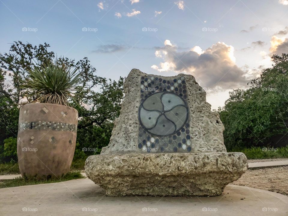 Public visual urban art inspired by Native American cultures at city park. Sculpture and bench.