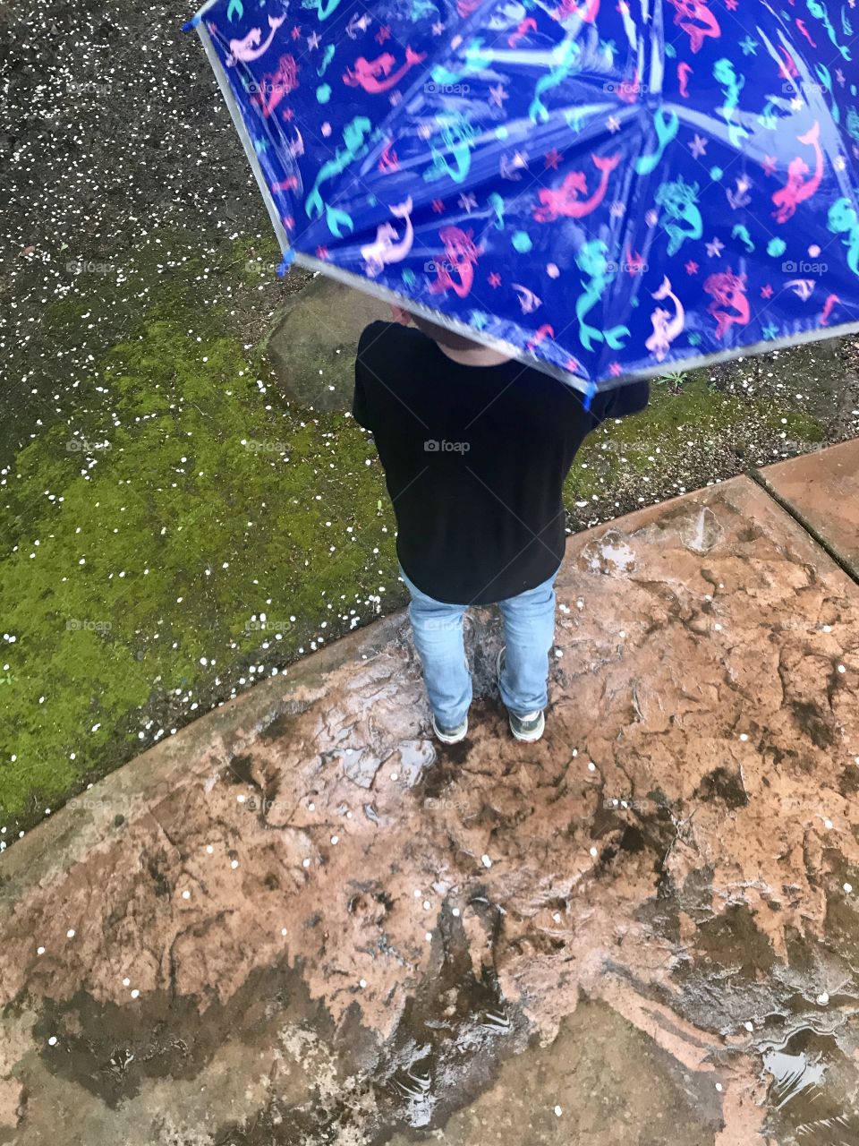 Standing outside in the rain  with a big umbrella 