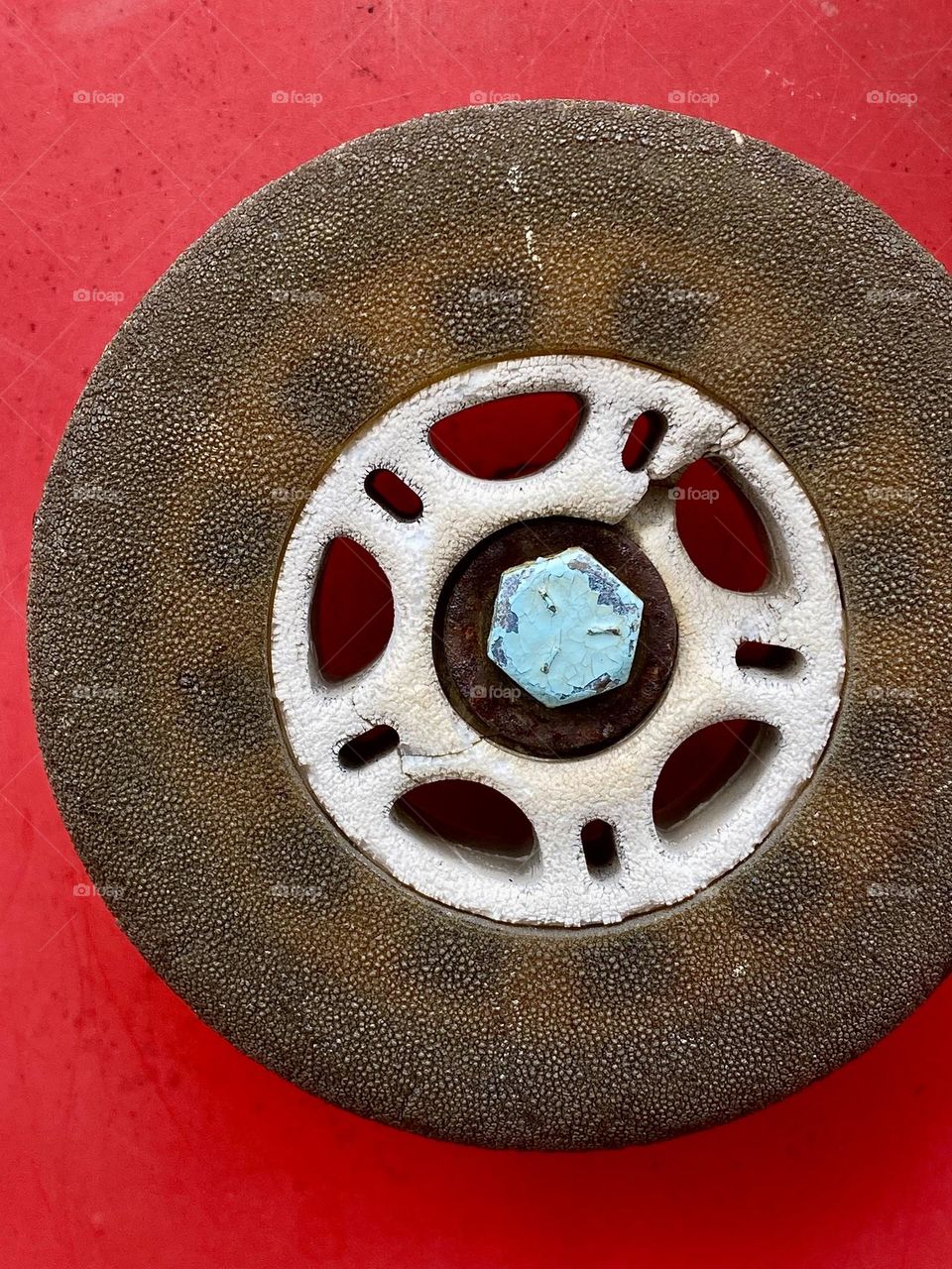 Close up of an old cracked rollerblade wheel on a bright red background