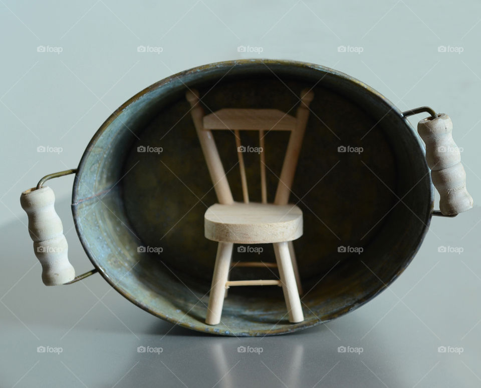 A closeup of a miniature toy chair sitting inside a miniature vintage Victorian era toy tub.