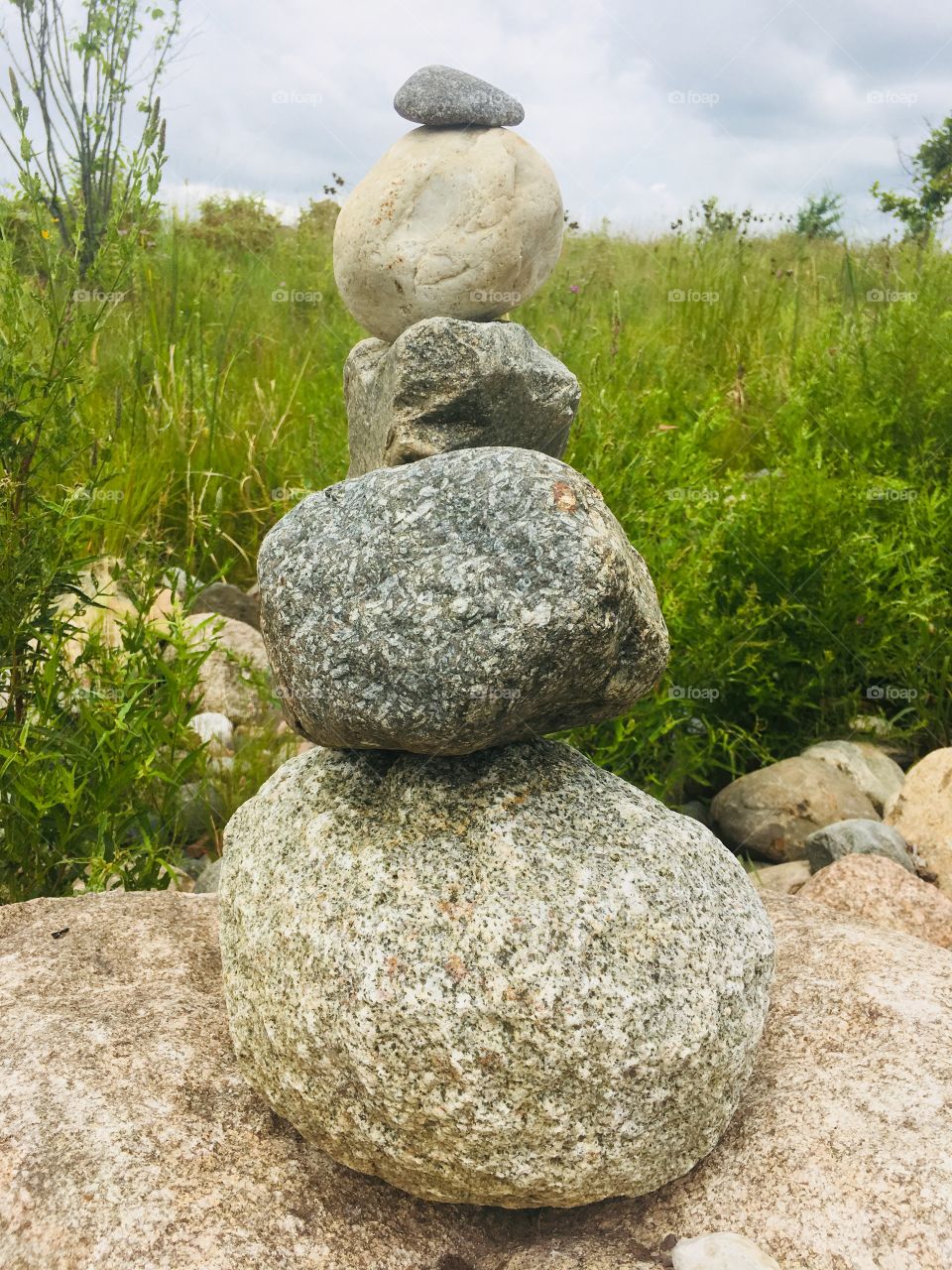 Gray and tan rocks stacked on top of each other against a muted green background  