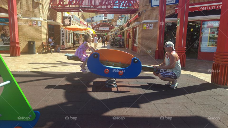 Father and daughter playing with see saw on street