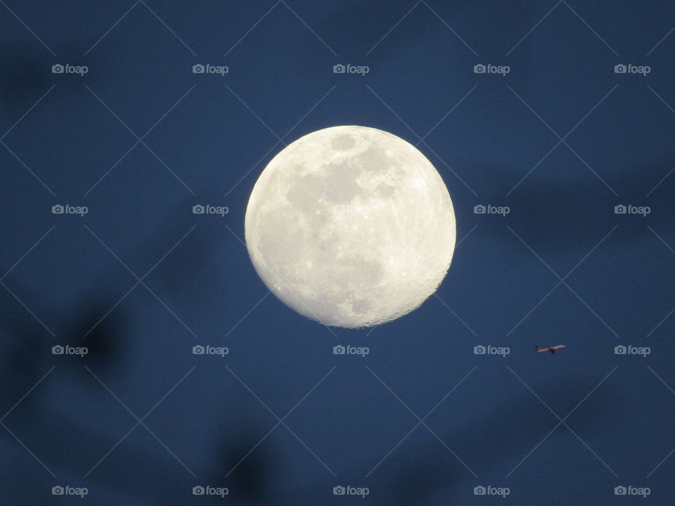 Bright full moon on a clear night reflects off a near by jet as it flys. 