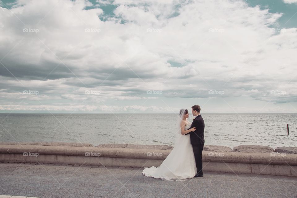 Bride and groom beside a lake with amazing clouds