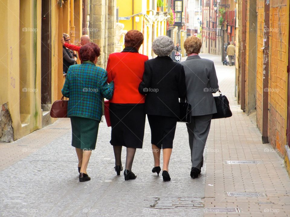 A four elderly ladies walk arm in arm after leaving church in Pamplona. 