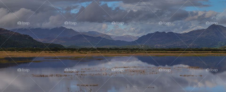 snowdon mountain range with clouds and lake reflections