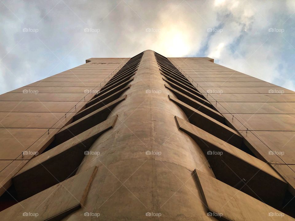 Looking up beside a tall building. Impressive is the key word here. And the clouds in the sky contribute for the great effect. Looking for symmetry, found beauty.