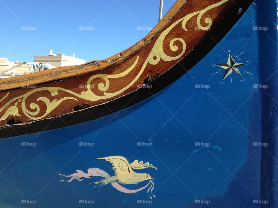 A boat anchored in the fishing village of Marsaxlokk, Malta. Boats are painted in bright colours blue, yellow, green, red