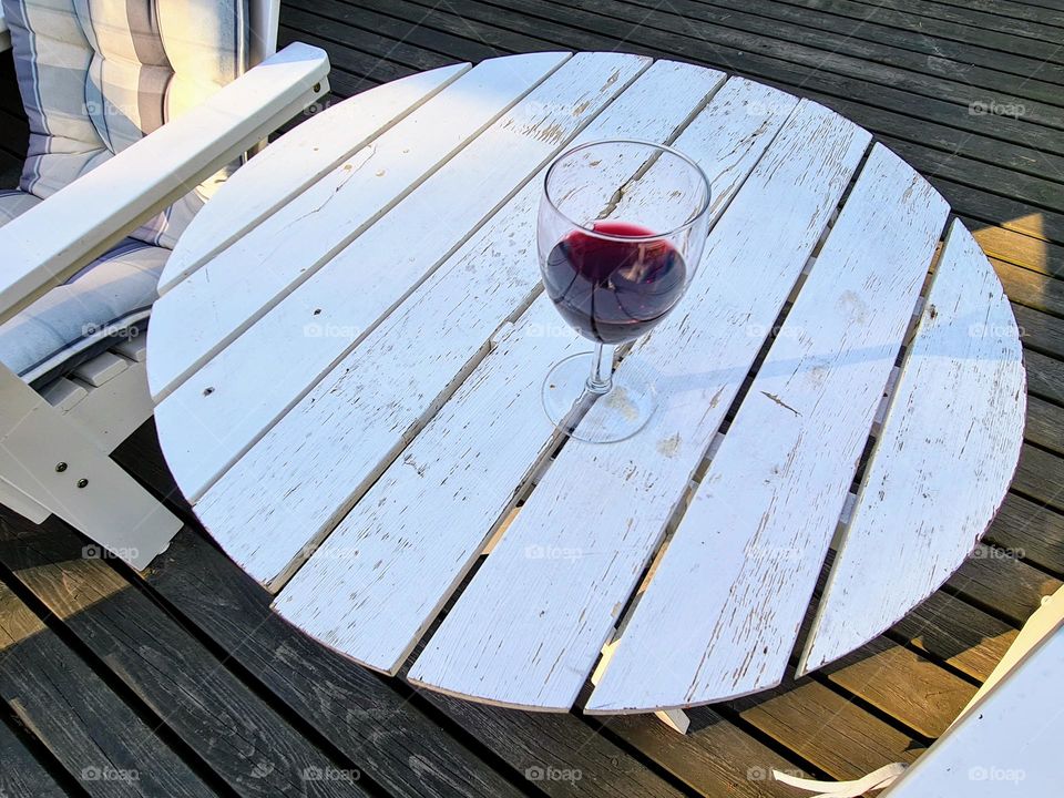 Round circle shape old wooden white plank table with the glass of red wine on it 