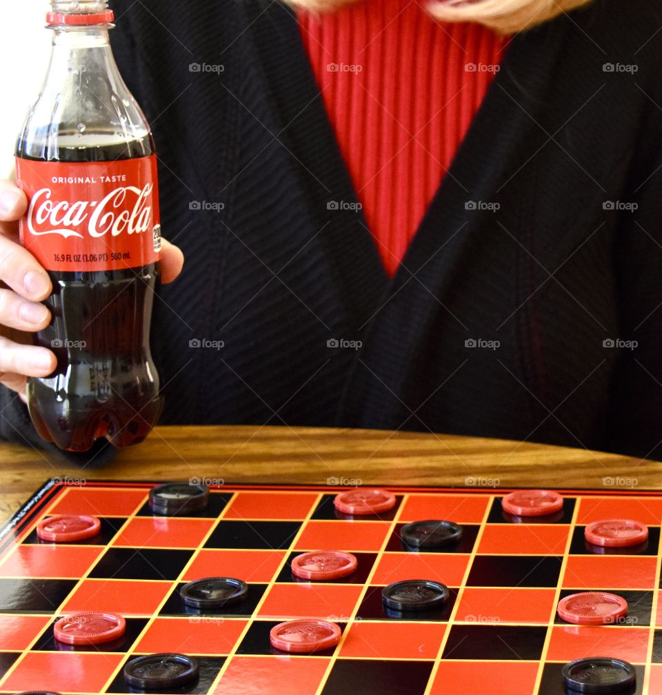 Woman drinking Coca-Cola and playing checkers 