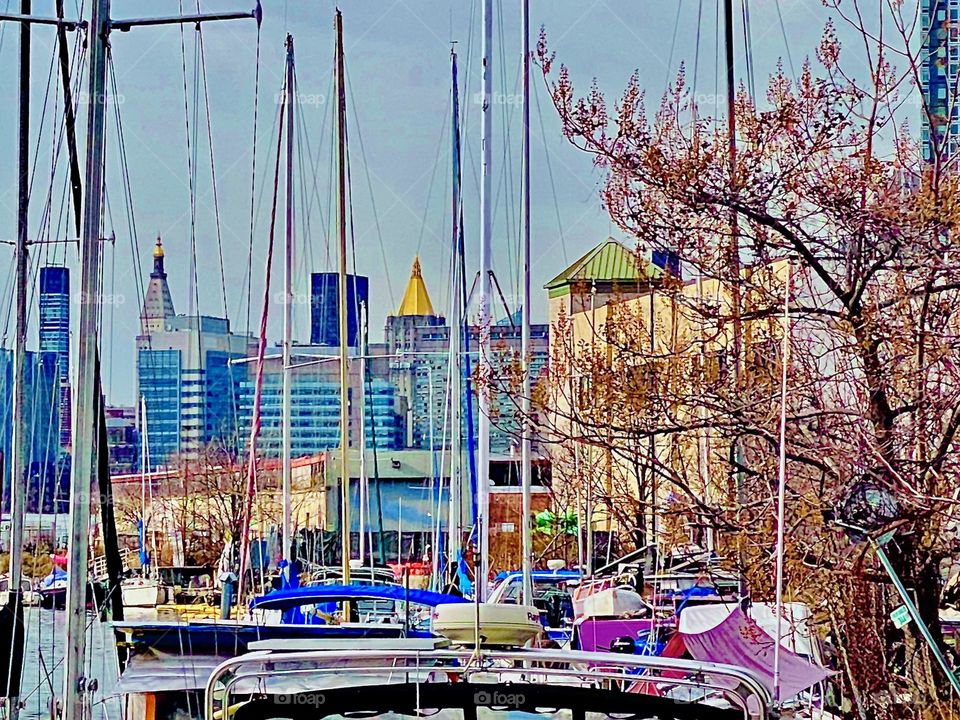 A zoomed view of Manhattan from beneath the Pulaski Bridge at Newtown Creek in LIC, Queens on an early afternoon in December 2021. Two landmarks, the “Empire State” and the “NY Life Bldg” with a golden roof can be seen. Hypnotic Productions