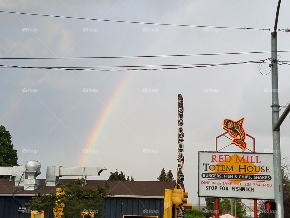 rainbow with faint second rainbow behind the Red Mill Totem House in Seattle, Washington 5/19/2016
