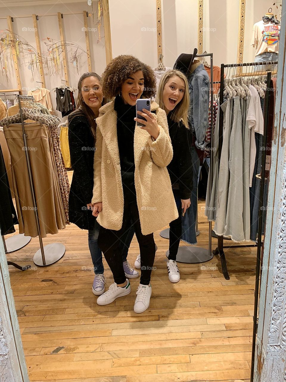 three beautiful friends being silly together as they shop in a clothing store in the city