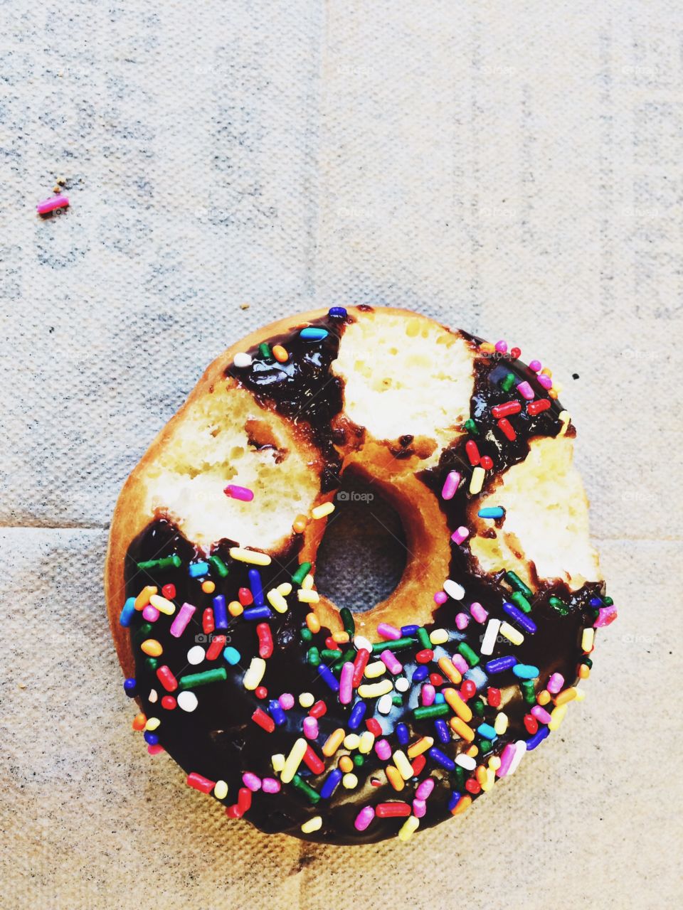 Three symmetrical bites out of a yummy, chocolate frosted with rainbow sprinkles donut. 