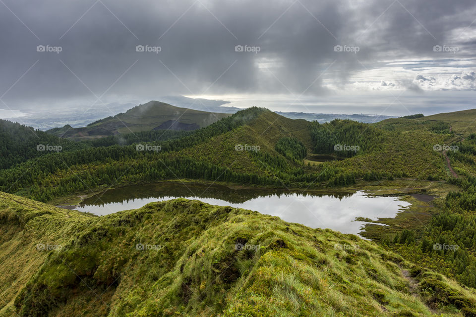 Hiking on the trail of Serra Devassa in Sao Miguel Island, Azores, Portugal. Vulcanic lake, clouds and reflection.