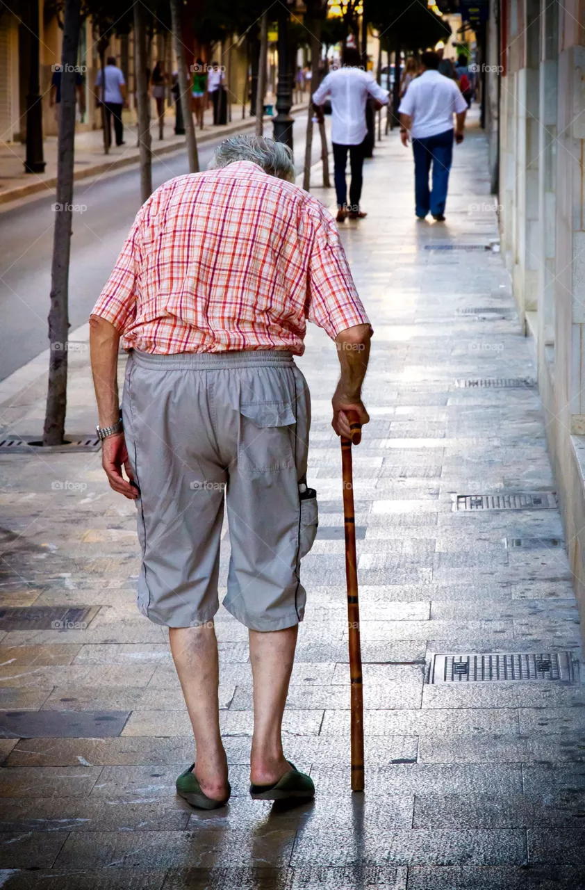 Rear view of old man walking on street