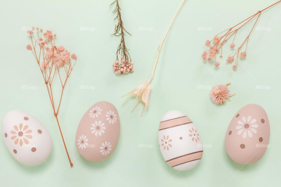 Peach & white decorated eggs with dried flowers on mint green background