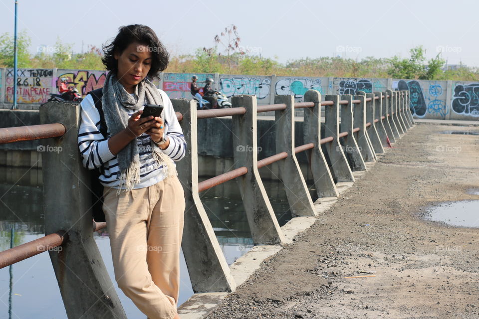 a traveller Woman Standing on the bridge & looking at her smartphone.