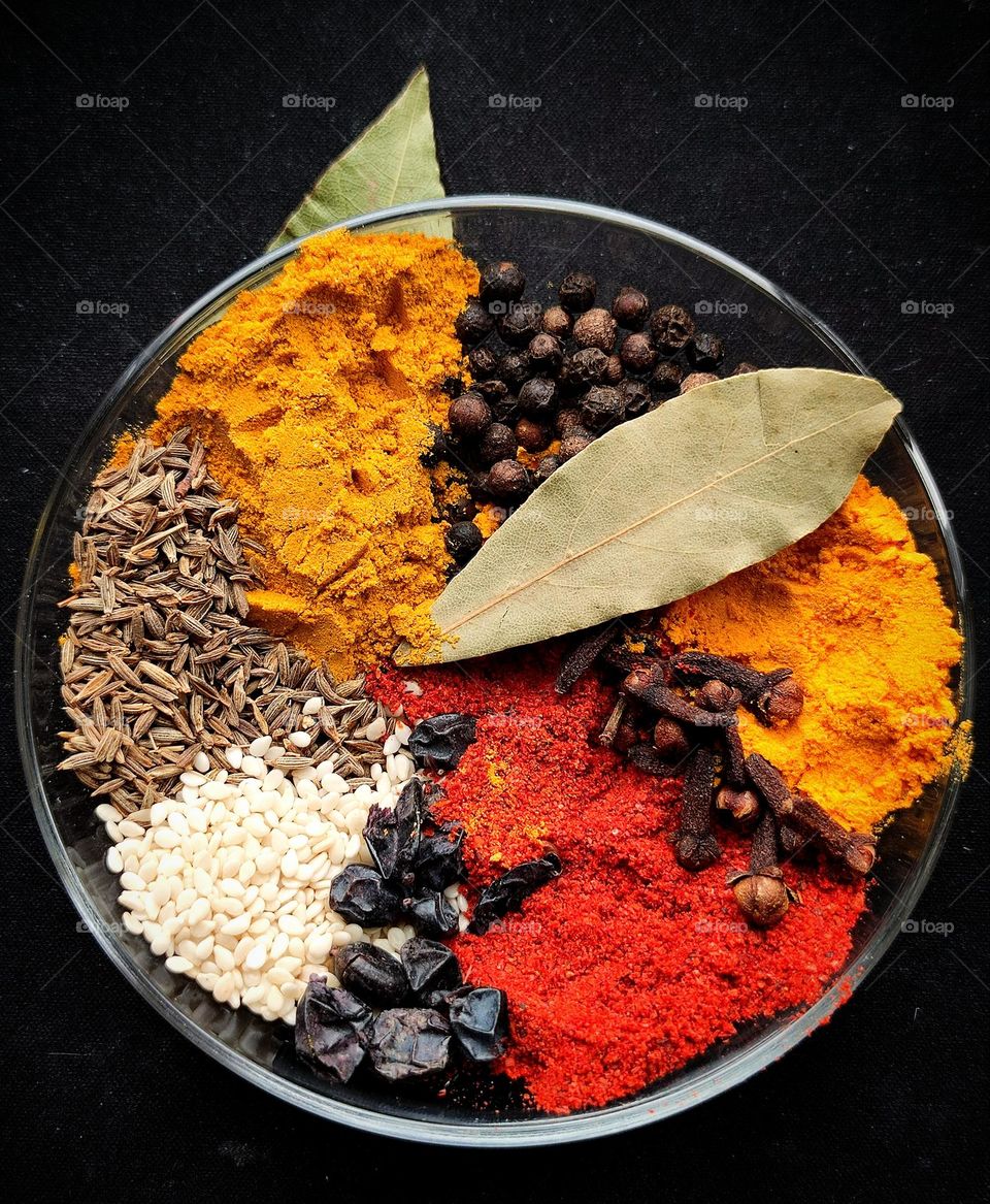 Spice flower fountain.  Red paprika, yellow turmeric, dark yellow curry, black peppercorns, black barberry seeds, white sesame seeds, brown cumin seeds and green bay leaves