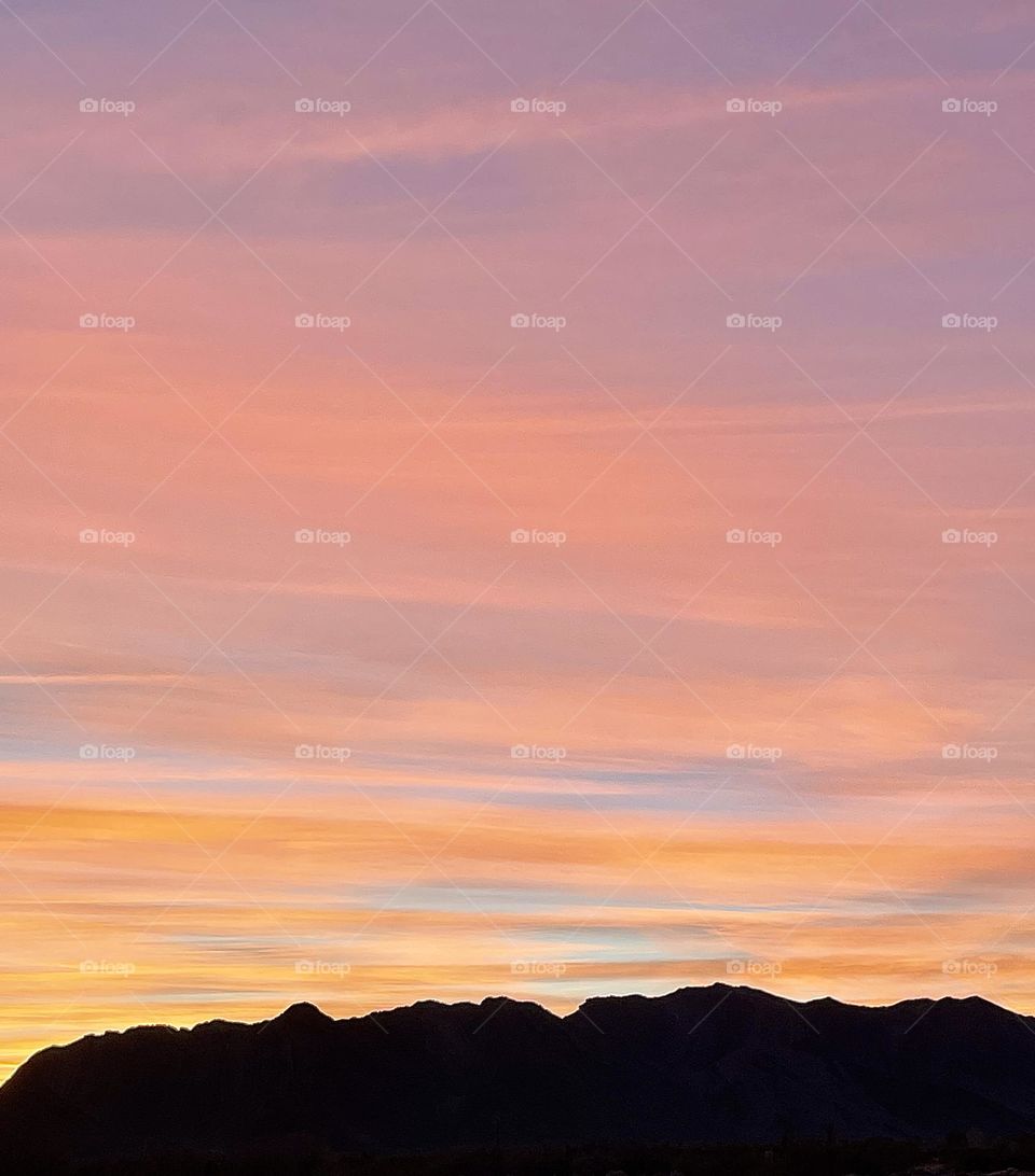 A photo of a pink and gold sunset above beautiful mountains. 