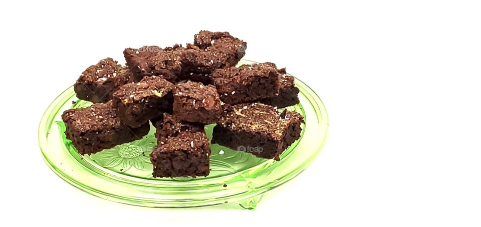 Chocolate brownies on a green glass plate with a white background 