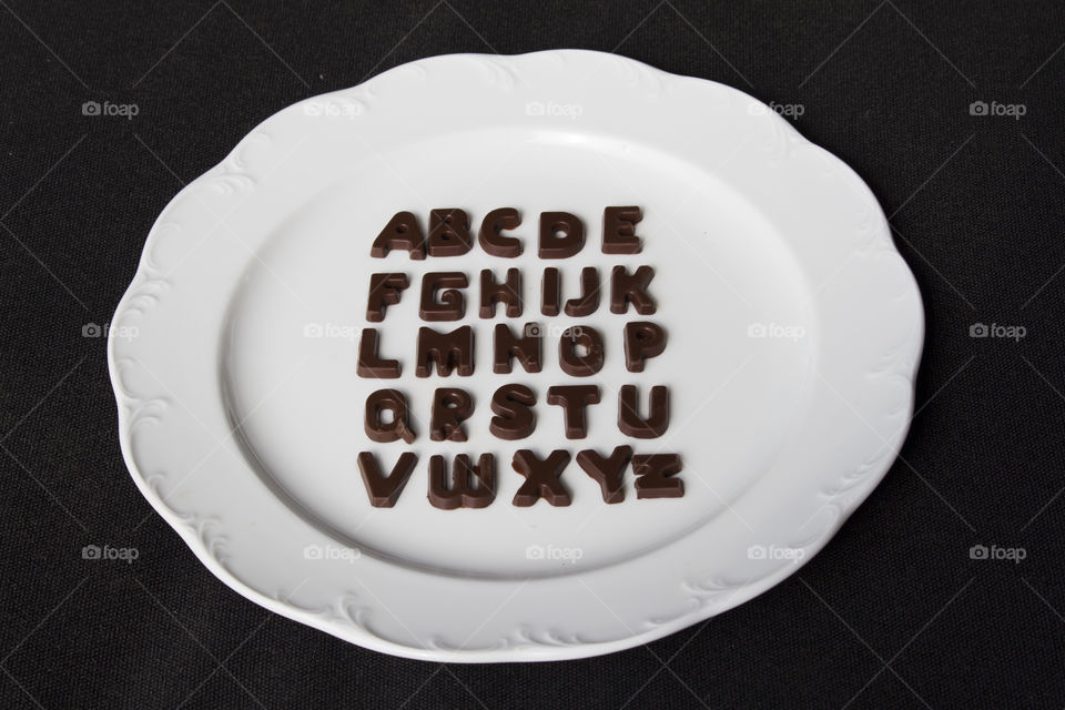 Alphabet chocolate letters on white plate 