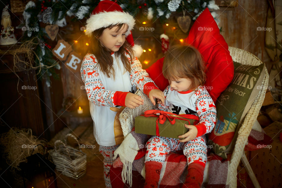 Little sisters near fireplace at Christmas Eve 