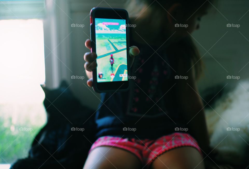Close-up of girl showing game on smartphone