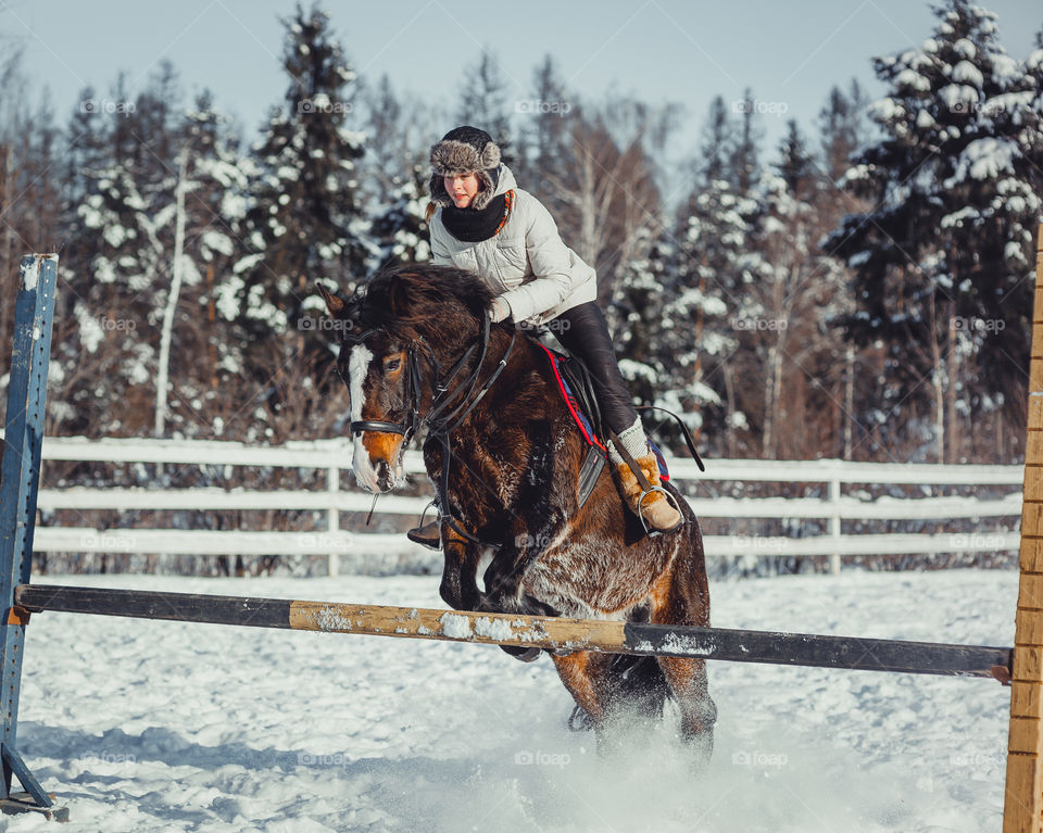 Teenage girl horseback jumping at cold winter day