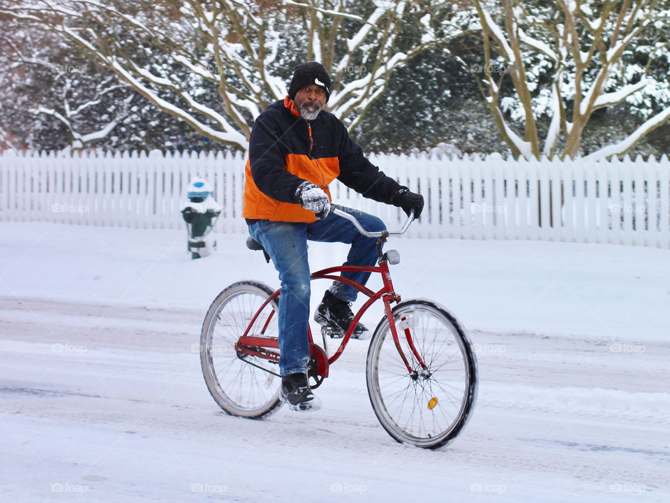 A man rides his bicycle down a snowy street in Easton, Maryland