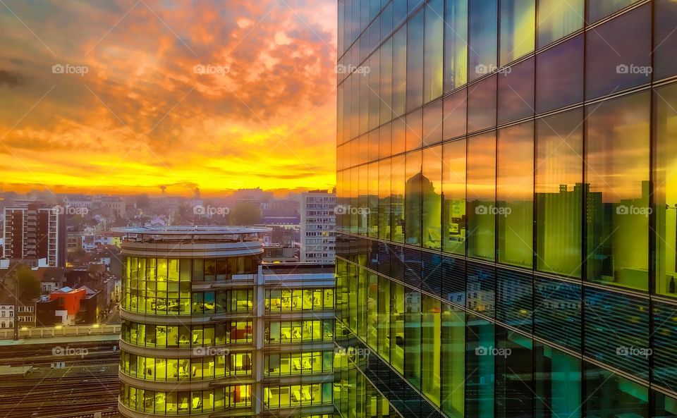 Dramatic and colorful sunrise sky over the city streets and reflected in the glass windows of a business office building