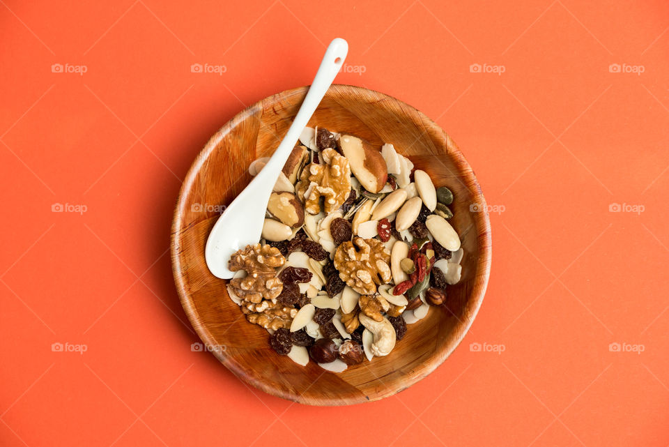 a mixture of nuts in a bowl, top view, complimentary colors, orange color