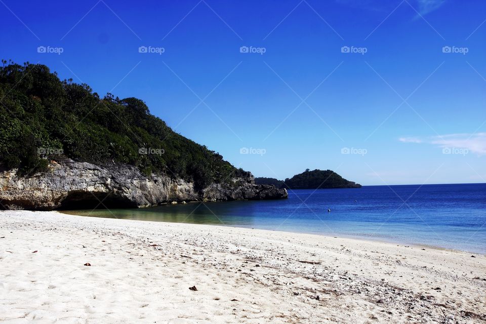 beach shore, blue ocean, clear sky and an island cove
