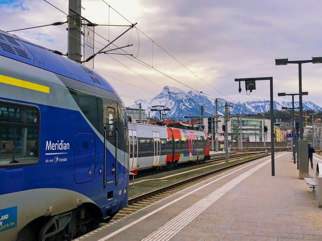 Train Station in Salzburg, Austria, with snow covered Alps Mountains in the background. Travel by train, Winter holiday, Vacation, Europe tourism, Ski resorts.