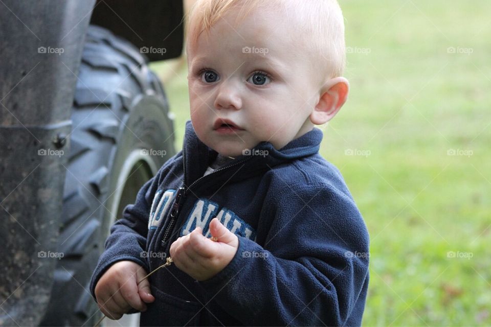 Cute little boy standing near vehicle