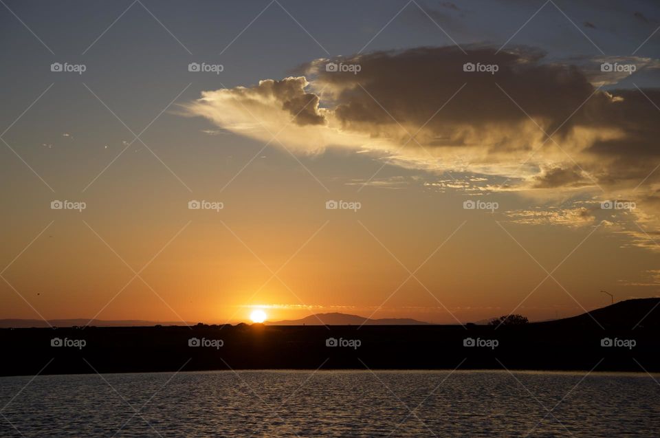 Patch of cloud above water photographed during sunset.