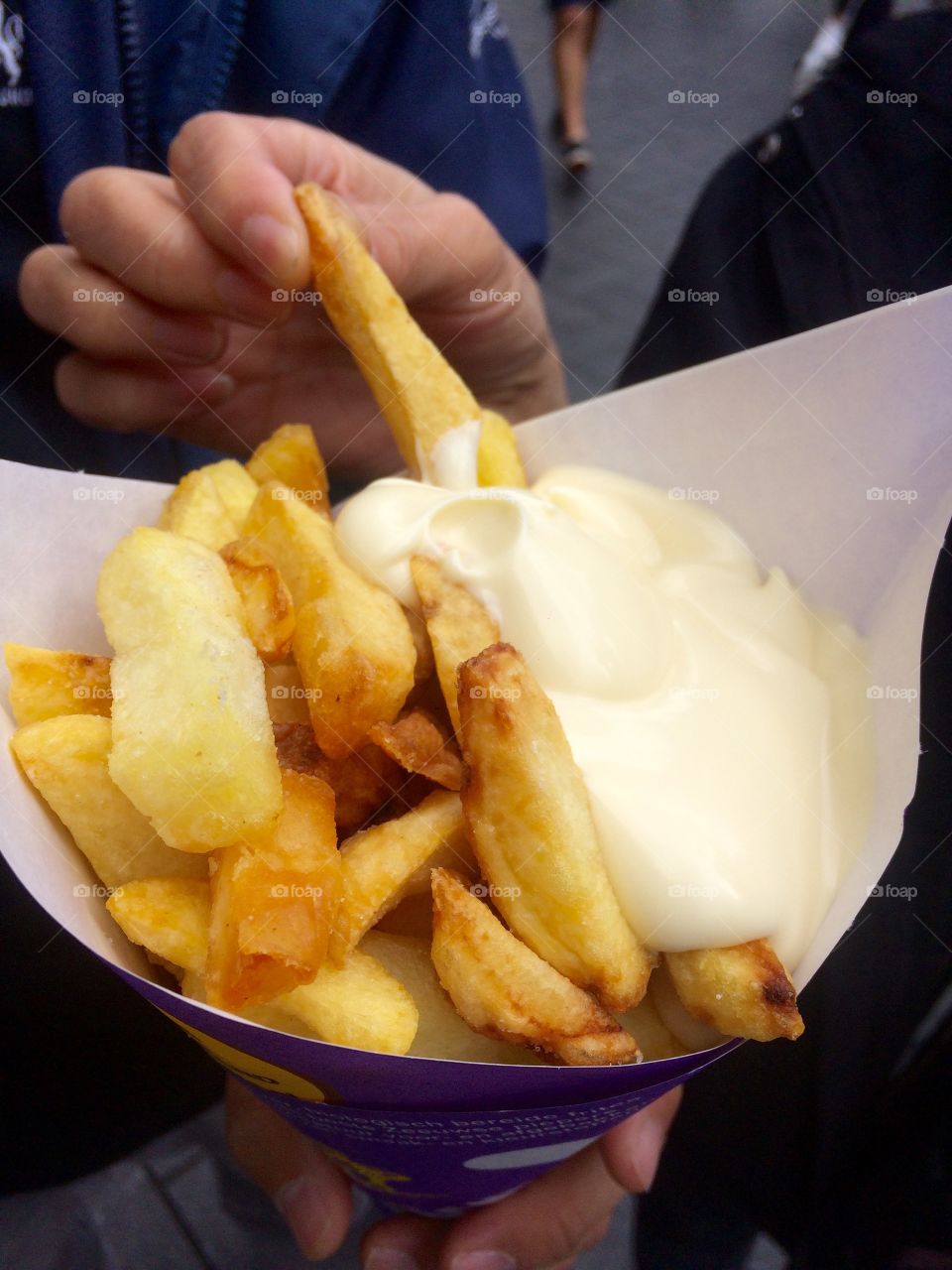 Close-up of person holding french fires with mayonnaise