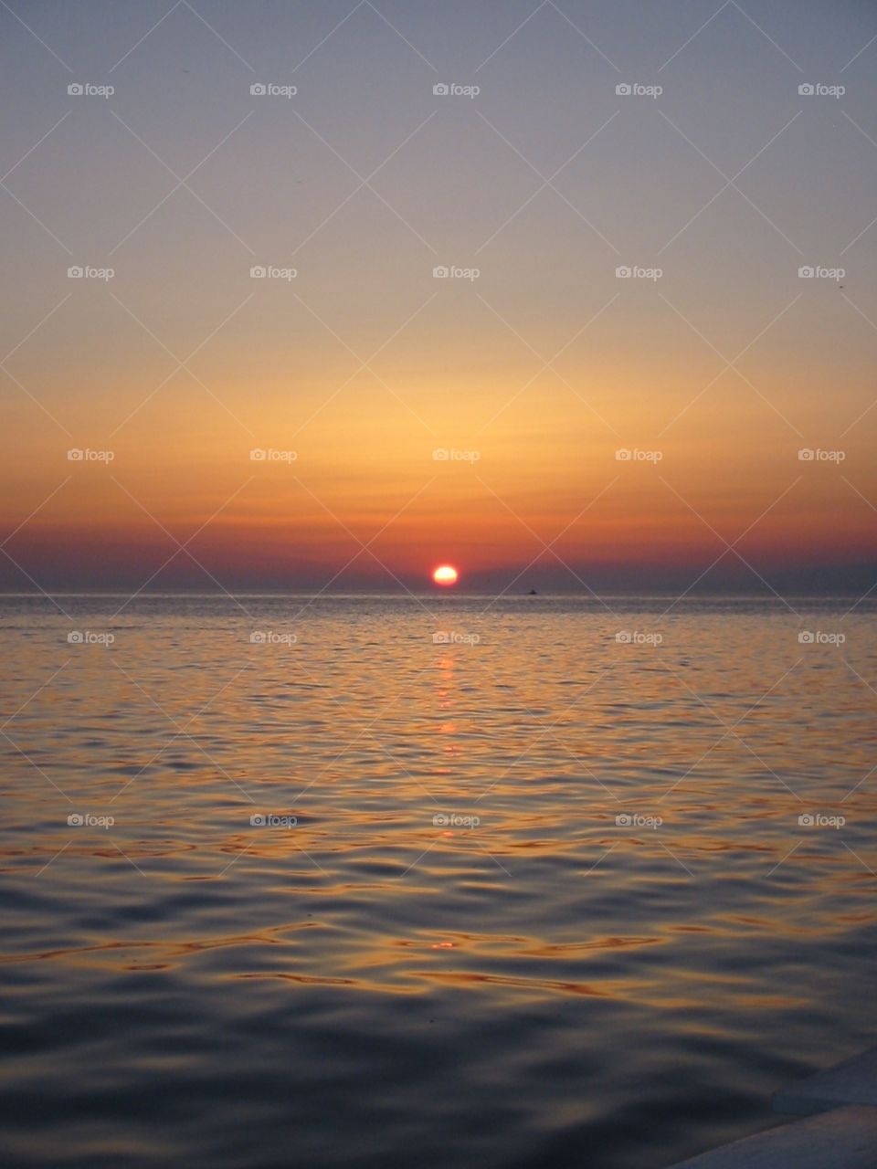 Gorgeous orange and yellow sunset from Little Venice in Mykonos, Greece on a clear summer’s evening.