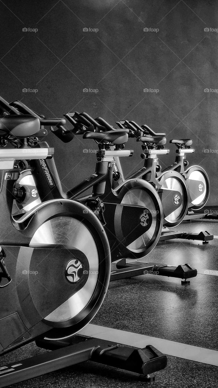 circular wheels of spinning bicycles in a gym studio. in black and white