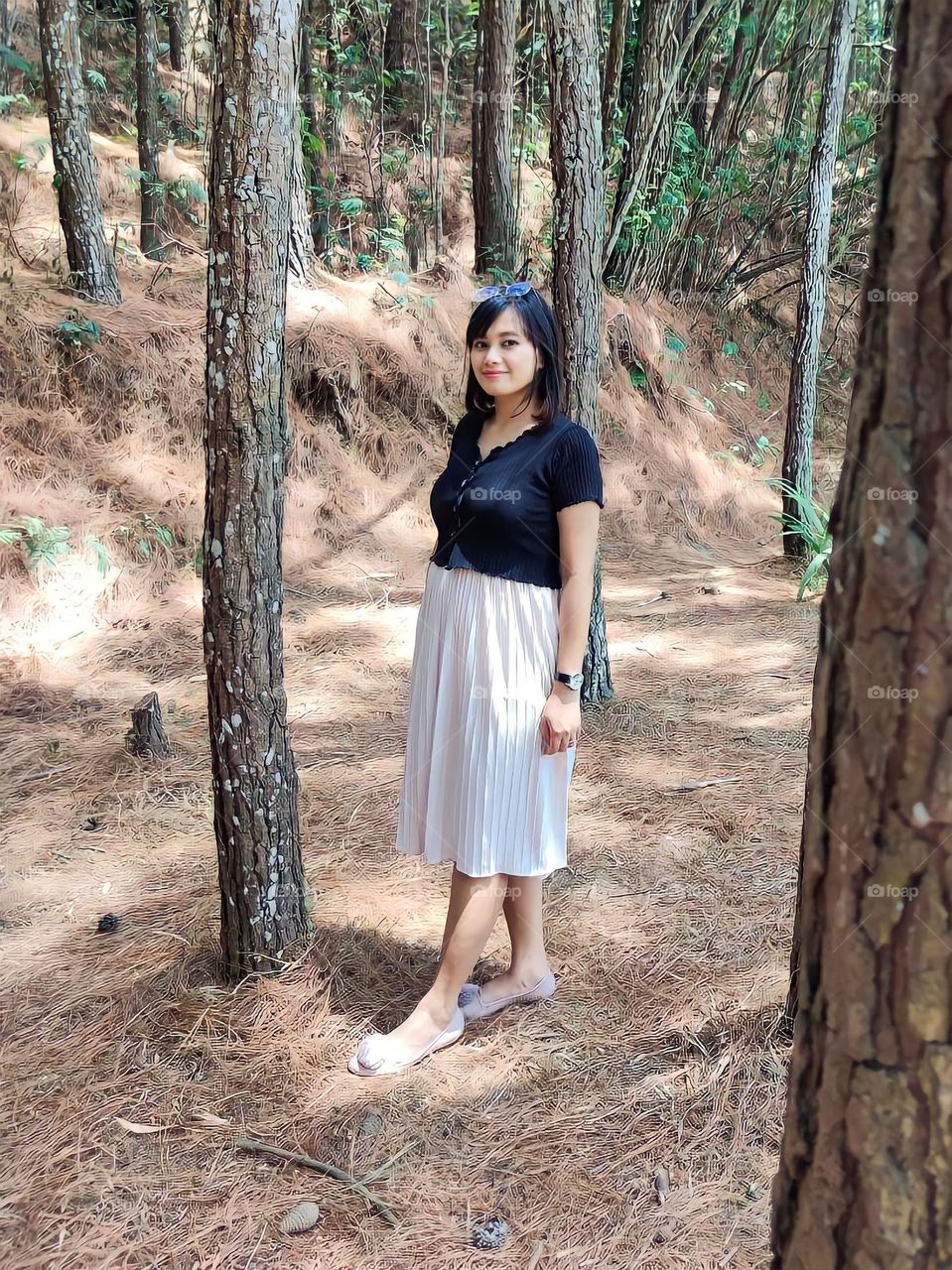 Portrait of a young woman standing looking at the camera in a pine forest area