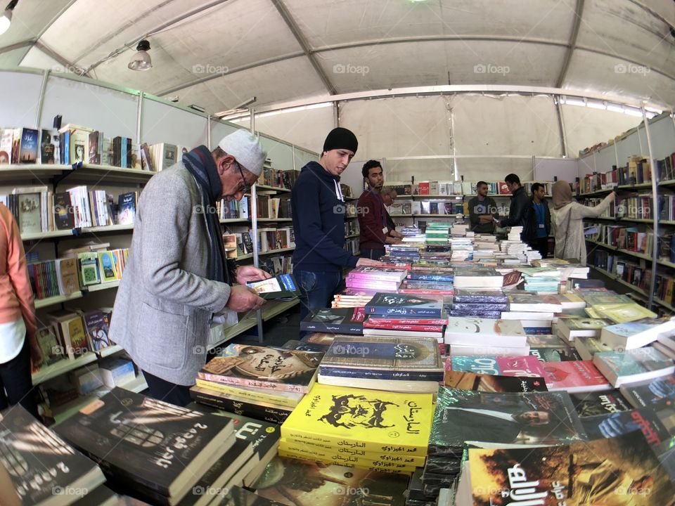 photo of an old man looking for a book in theinternational  book fair in egypt 2018
