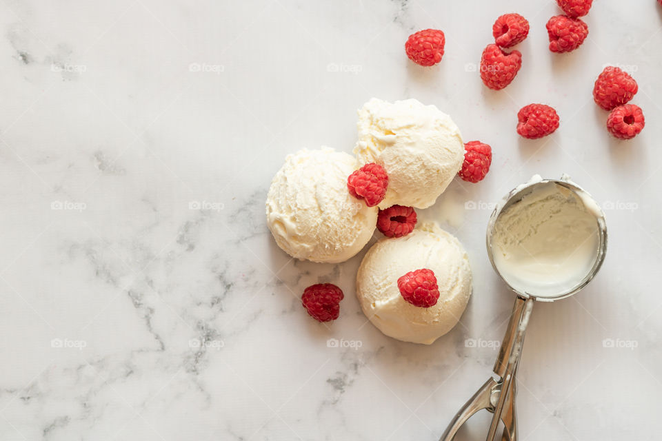 Top view and selective focus to homemade vanilla ice cream and some raspberries fruits on the table. Copy space.
