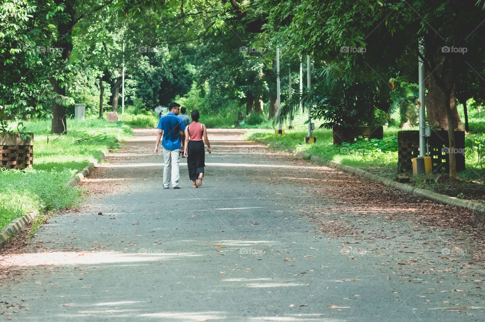 Portrait of two joyful young loving Couple walking in a green autumn park on a romantic summer day. Pre-wedding marriage engagement concept. Togetherness composition. Botanical garden, Kolkata, India