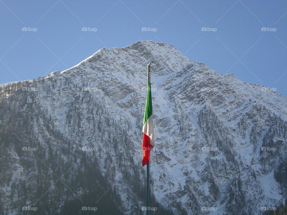 the italian flag raised up in front of alps mountain unwindy