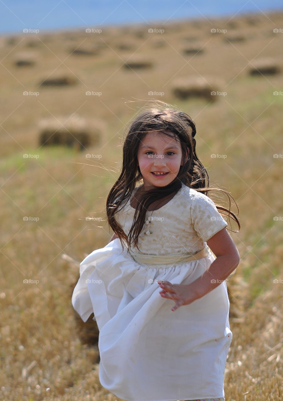 Girl running around in a field. Cute little girl running through a field